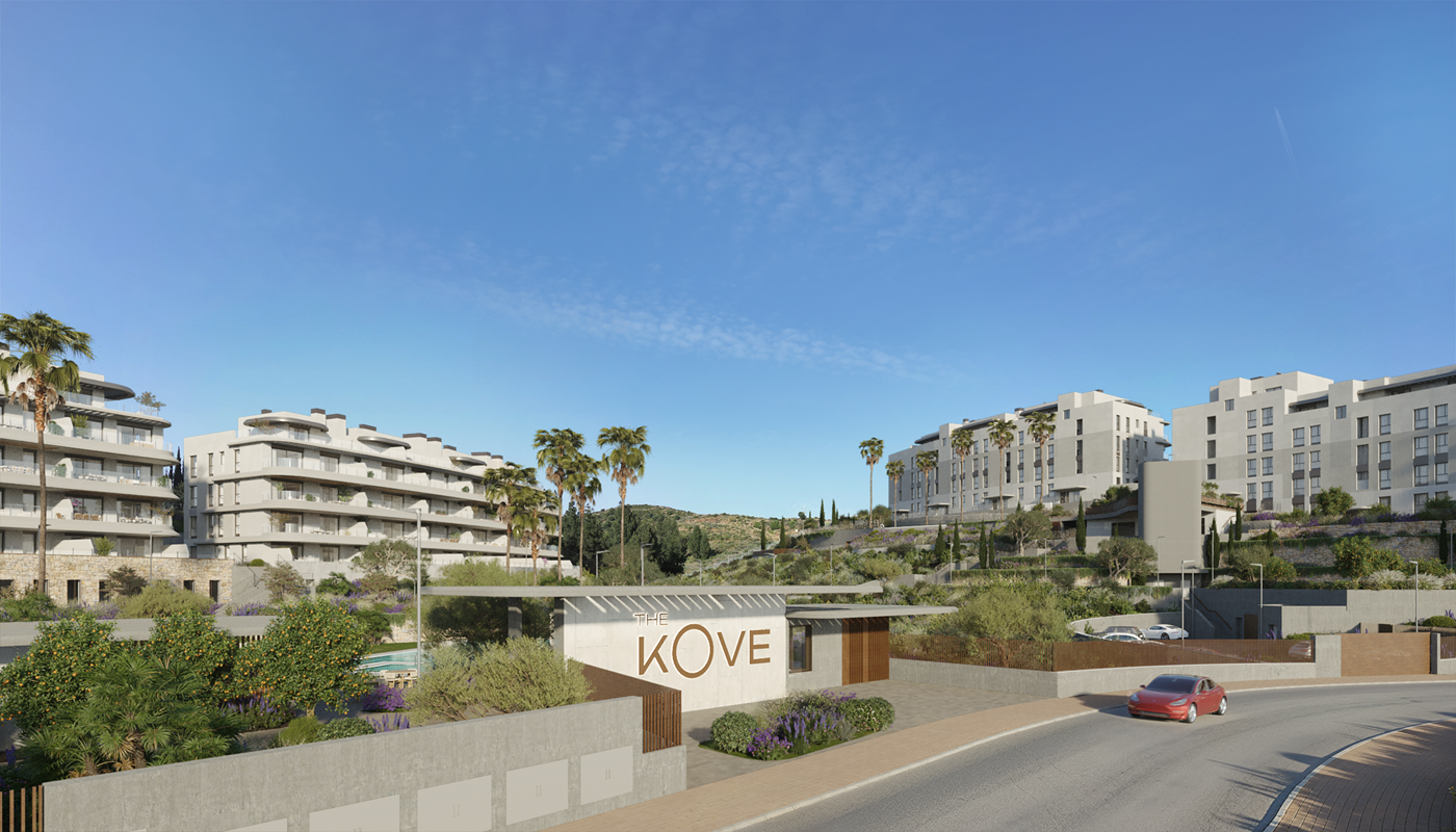 Modern residential complex entrance with palm trees and contemporary buildings in a scenic hillside setting.